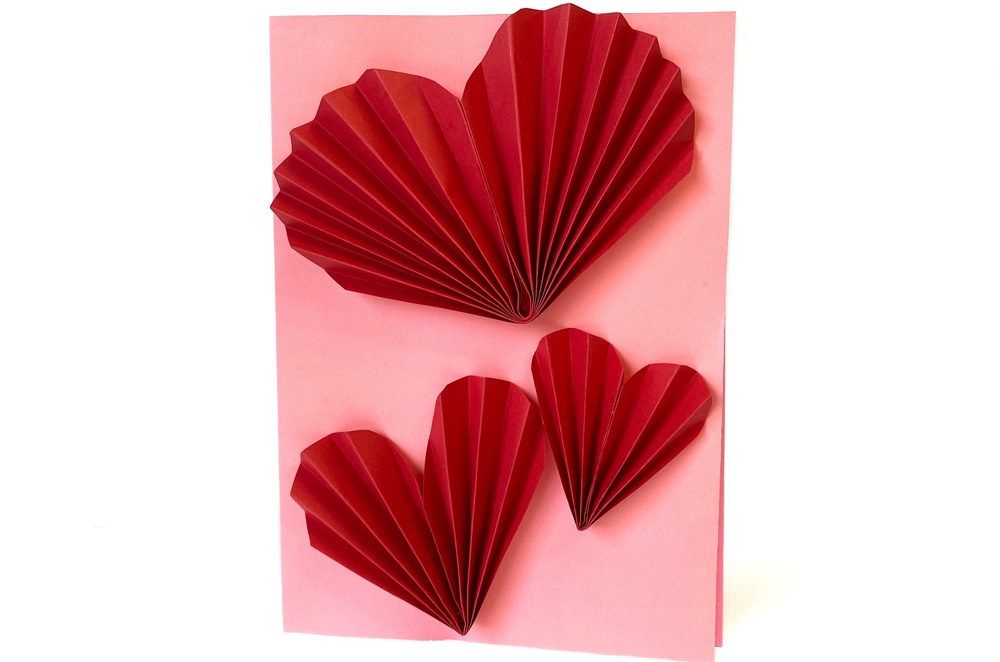 Rosa kort med tre vikta röda hjärtan i olika storlekar